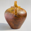 Side angle highlighting the wide body tapering down to a narrow foot with a smooth clay texture and ochre glaze variations.