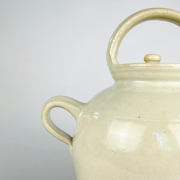 Large white glazed terracotta jug from France with an elongated ovoid body, gently tapered foot and hand-thrown rings visible beneath the glaze. Twin handles frame the wide neck, while the small pouring spout adds a distinctive architectural detail suited to farmhouse decor and neutral antique pottery collections.