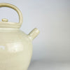 Antique French pottery jug showing one substantial loop handle joined between the rolled rim and rounded shoulder. Variations in the ivory glaze, scattered dark specks and light rubbing reveal the handmade fired-clay surface of this early 20th century cruche pot, now presented as a decorative folk object.