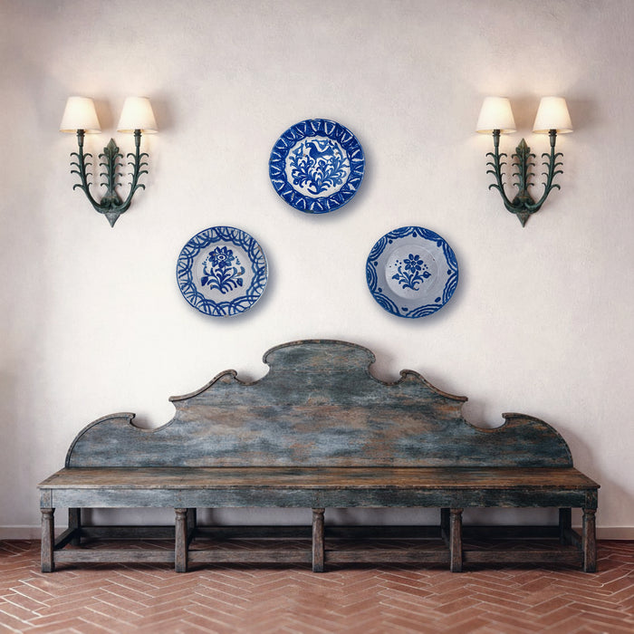 Three blue and white decorative plates on a wall above an old wooden bench. French Country Decor and Cottage Decor interiors