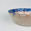 Ceramic bowl with blue patterns on a white background. Close-up of the central floral bouquet motif on an antique Spanish lebrillo bowl, revealing layered cobalt brushstrokes, glaze pooling, and soft cobalt bleed into the tin glaze. This Granada pottery piece works as wall hanging ceramic decor or a serving bowl on open shelving, ideal for Wabi Sabi decor and Japandi interiors focused on authentic surface character.