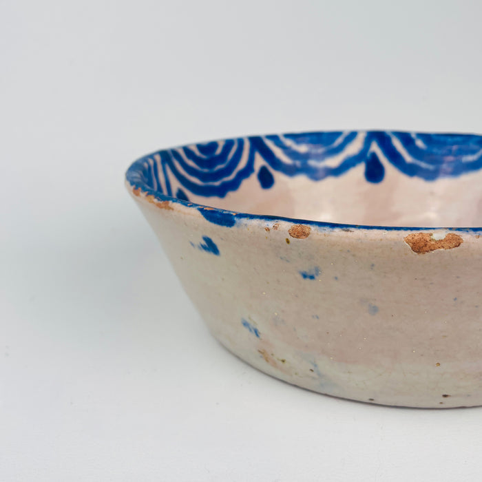Ceramic bowl with blue patterns on a white background. Close-up of the central floral bouquet motif on an antique Spanish lebrillo bowl, revealing layered cobalt brushstrokes, glaze pooling, and soft cobalt bleed into the tin glaze. This Granada pottery piece works as wall hanging ceramic decor or a serving bowl on open shelving, ideal for Wabi Sabi decor and Japandi interiors focused on authentic surface character.