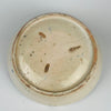 Close-up of a ceramic bowl's base with visible wear and tear on a white background