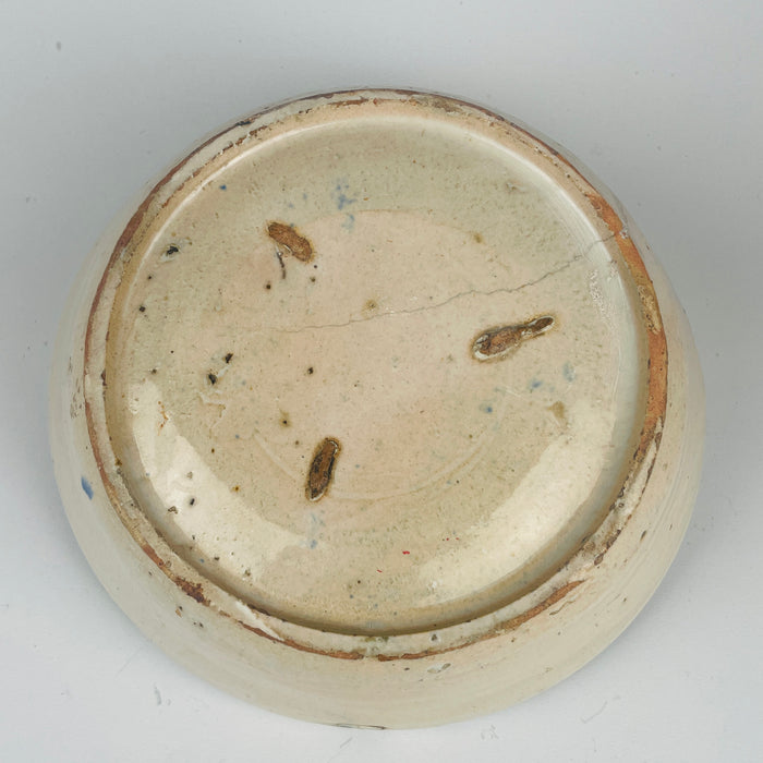 Close-up of a ceramic bowl's base with visible wear and tear on a white background