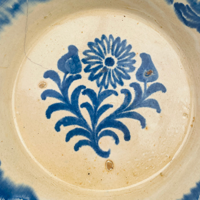 Granada Fajalauza tradition style bowl in tin glazed terracotta, decorated in cobalt blue with a central flower and two bud forms on curling stems. The broad blue rim band frames the interior and gives strong contrast against the creamy glaze. Use as a tapas serving bowl, table centerpiece, or ceramic accent for Mediterranean decor interiors.