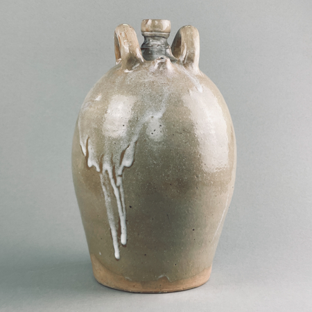 Antique glazed stoneware jug with twin handles and natural drip glaze.