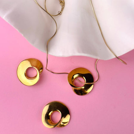 Minimalist gold sculptural pendant designed by Laragh Stuart, hand-carved in wax and cast in bronze using the lost-wax method, then plated in 14k gold. This wearable sculpture features organic asymmetrical curves and a central cut-out, created as contemporary art jewelry.
