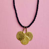 Hero shot emphasizing the reflective surfaces of the three hammered discs against neutral backdrop. Keywords: gold-tone hammered necklace, minimalist jewelry, layering pendant accessory.