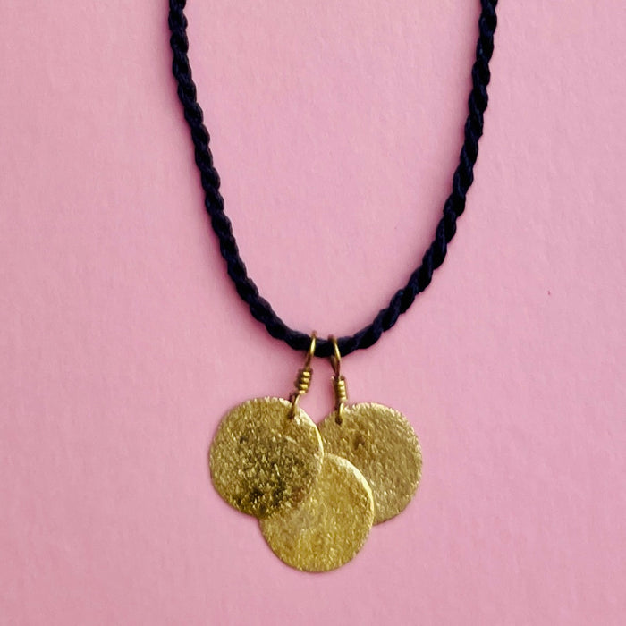 Hero shot emphasizing the reflective surfaces of the three hammered discs against neutral backdrop. Keywords: gold-tone hammered necklace, minimalist jewelry, layering pendant accessory.
