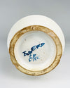 Underside of a vintage Spanish Talavera style albarello jar showing a handwritten cobalt blue inscription and secondary painter's monogram inside the recessed circular base. The surrounding foot ring exposes buff-coloured pottery with surface wear and residue. These visible markings and construction details are important identifying characteristics of this hand decorated ceramic apothecary vessel.
