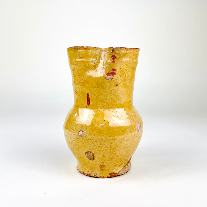Spanish folk pottery jug in warm yellow glazed earthenware, sourced in Peñafiel in the province of Valladolid. The handmade pitcher combines a pinched spout, gently irregular rim and loop handle with a compact 15.5 cm form, making it a strong antique ceramic accent for rustic home decor and collected Mediterranean pottery.