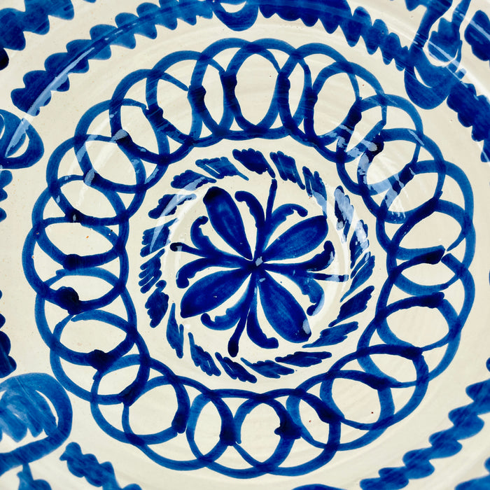 Exterior detail of the Spanish Los Arrayanes bowl showing a broad cobalt blue motif beneath the painted rim, with natural tonal variation where the pigment pools and thins. The cream glazed earthenware surface retains small artisan irregularities, supporting the handmade character of this large Fajalauza serving bowl and Mediterranean ceramic decor.