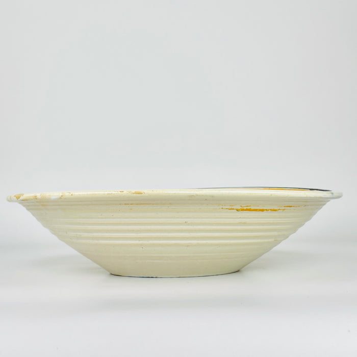Early 20th century Spanish remolino lebrillo made from hand thrown glazed pottery, with a cream field framed by concentric green, ochre and black bands. Cobalt blue leaves alternate with rounded green flowers around the central spiral, creating strong movement and balanced color for Mediterranean decor, a plate wall or tabletop display.