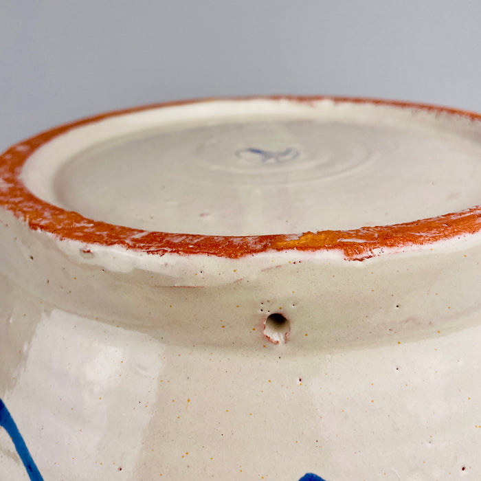 Pierced hanging hole within the foot ring of the large Los Arrayanes Fajalauza bowl, allowing the ceramic to be displayed as Spanish wall art. The surrounding base shows exposed reddish terracotta, glaze rubbing and handmade surface texture, all consistent with the construction and previous display of this heavy Granada pottery lebrillo.