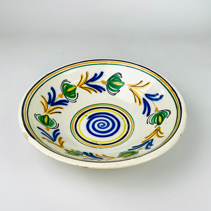 Shallow flared profile of an early 20th century Spanish ceramic lebrillo, with a low foot ring, broad rim and rhythmic wheel thrown ridges around the exterior. The cream glaze and traces of ochre pigment continue over the edge, while minor rim wear and glaze losses support its authentic age and rustic home decor character.