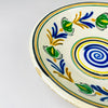 Antique Spanish lebrillo bowl identified by its 28.5 centimeter width, 7 centimeter height and 800 gram weight. The early 20th century glazed earthenware has a Castilian remolino arrangement of cobalt blue leaves, green flowers, yellow branches and black outlines around a spiral centre, useful as ceramic wall art or a shallow decorative basin.