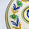 Hand painted Spanish lebrillo from the early 20th century, featuring a cream glazed ground, cobalt blue spiral centre and a continuous garland in green, yellow and black. The circular composition is easy to read from across a room, making this folk pottery bowl a strong focal point for eclectic decor, collected ceramics or a colorful plate wall.