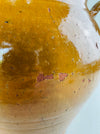 Provencal antique confit jar with ochre glaze drips and aged earthenware surface.
