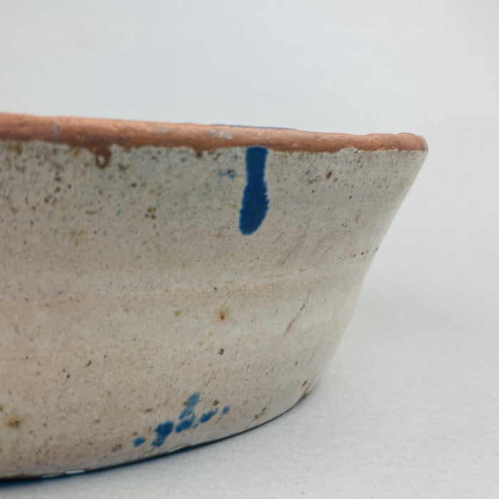 Side profile of the Spanish lebrillo showing the depth of the terracotta bowl and the hand-applied cobalt blue designs climbing the curved interior walls, emphasizing its rustic Andalusian craftsmanship and utilitarian origins.