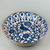 Top-down view of a large vintage Fajalauza ceramic bowl with bird motif and geometric Moorish scrollwork, radiating outward from the center in deep cobalt blue glaze on a softly aged white background, typical of Granada folk pottery.