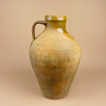 Side view of the Spanish cántaro earthenware jug, highlighting the elegant curvature and single loop handle typical of Burgos pottery. The soft transition from glazed to raw clay emphasizes traditional craftsmanship suited for wabi sabi interiors.