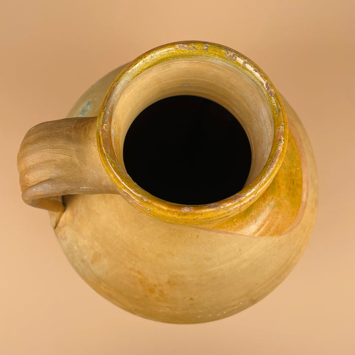 Clay jar with a handle on a beige background. Full ambient view with warm tones, showcasing the cántaro’s sculptural form and natural patina under soft light—an essential statement piece for wabi sabi, farmhouse, or organic modern interiors.