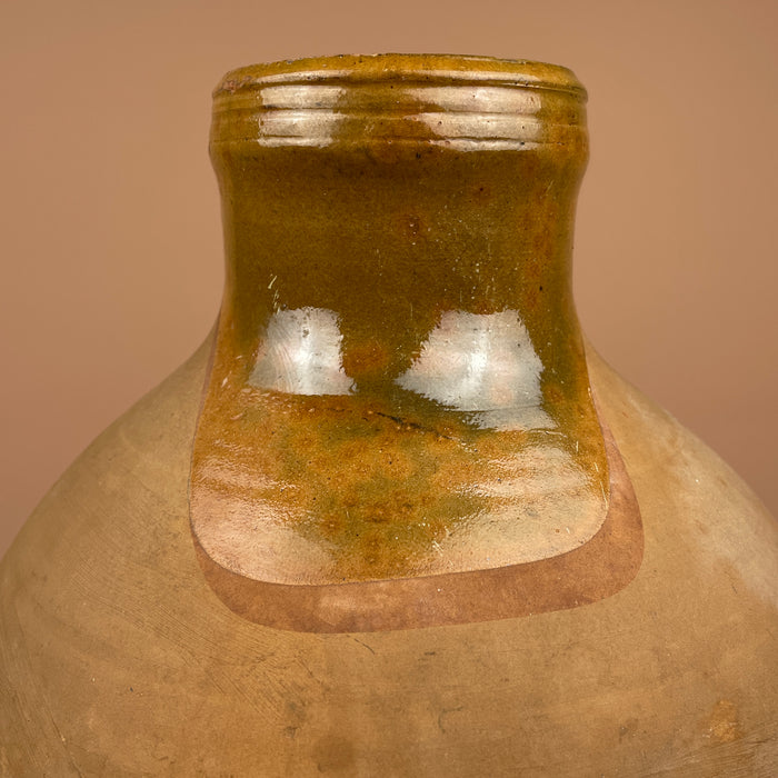 Close-up of a ceramic jar with a brownish-green glaze. Three-quarter view of the cántaro jug emphasizing symmetry and natural patina. Its hand-formed spout and handle pair perfectly with neutral-toned interiors and organic Mediterranean design.
