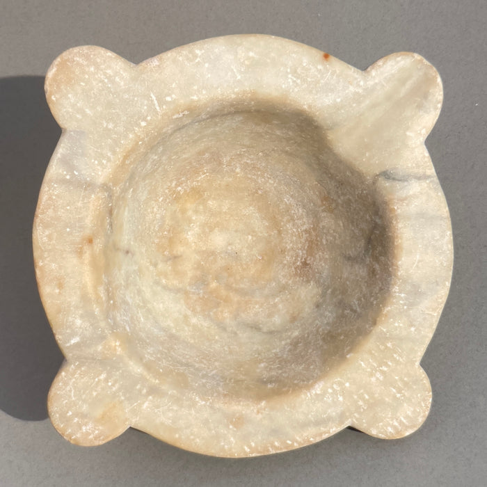 Side view of antique French marble mortar with sculpted handles and patinated stone surface, traditional apothecary tool.