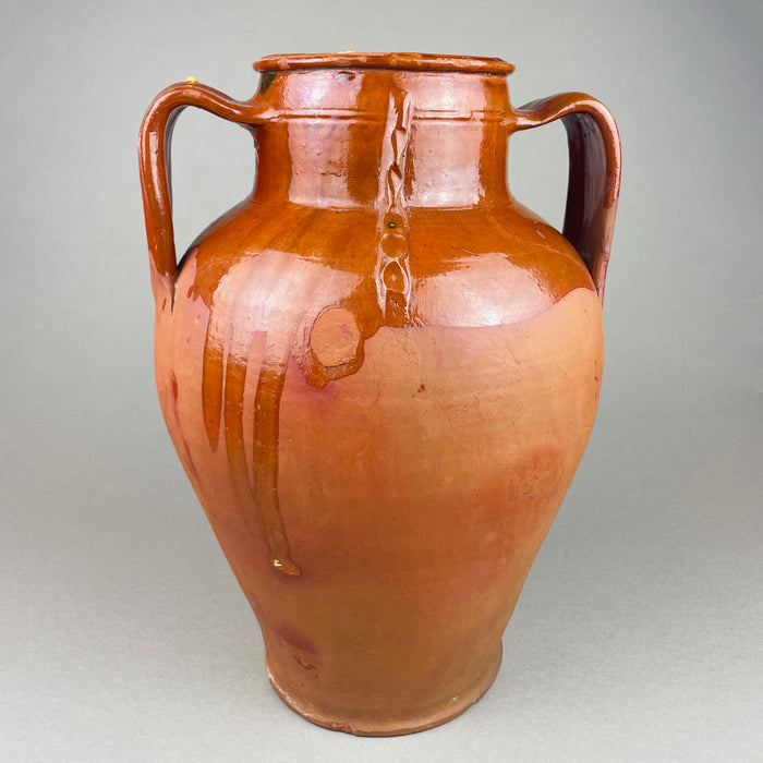 Top view into a large terracotta decorative jar with twin handles, showing the thick rounded rim, interior wear, and the contrast between glossy brown glaze and exposed clay at the lip. This antique decorative pottery piece reads well in wabi sabi and Japandi rooms where texture and patina are key.