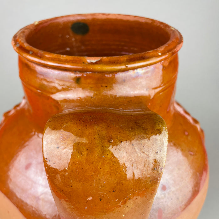 Rear view of the antique terracotta pot, highlighting the twin handles, glaze runs, and subtle color shifts from firing—brown, ochre, and red clay tones. This decorative pottery vessel can anchor a console or open shelf, aligning with rustic home decor, farmhouse decor, and collected ceramic displays.