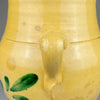 Detail image of the Spanish orza showing symmetrical leafy green strokes and brown accents hand-painted on the body. This botanical motif is characteristic of Andalusian folk pottery from Lucena, Córdoba, Spain.