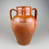 Antique terracotta decorative pot with twin handles, warm red clay body, and a glossy brown slip glaze that pools around the shoulder and neck. The ovoid form and wide mouth read as a decorative vase for vintage home decor, styled as farmhouse decor or French country decor with wood, linen, and natural tones.