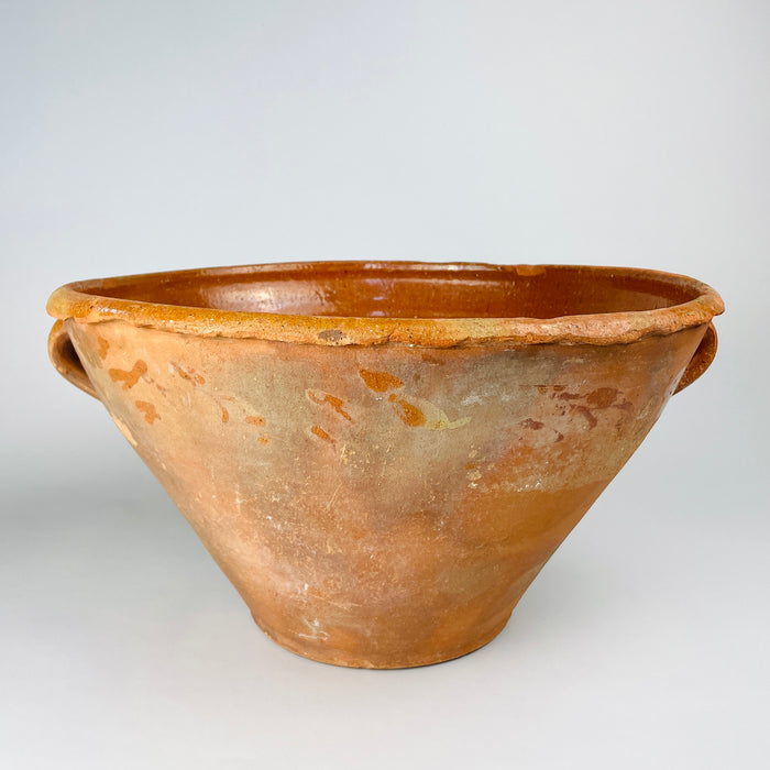 Antique XL Spanish lebrillo bowl dating to the late 18th century, wheel-thrown in warm terracotta with a deep conical body, broad rolled rim and two applied loop handles. The honey-brown glazed interior contrasts with the timeworn exterior patina, creating a substantial decorative vessel for farmhouse decor, Mediterranean decor and rustic home decor.