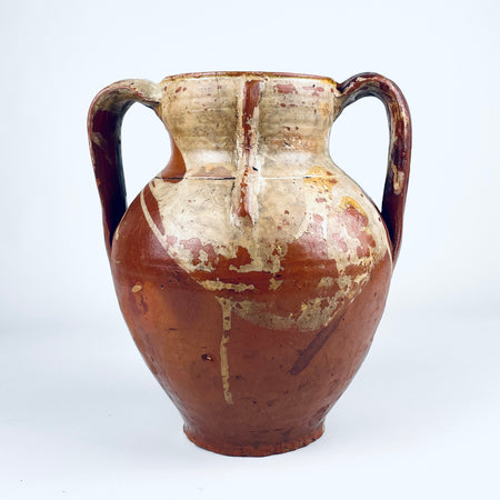 Antique Spanish glazed terracotta vase from nineteenth century Castile, formed as a traditional two handled orza pottery jar. The rounded red clay body has a short neck, open mouth, amber brown glaze across the upper section, exposed terracotta below, and age worn patina suited to Mediterranean decor or farmhouse decor.