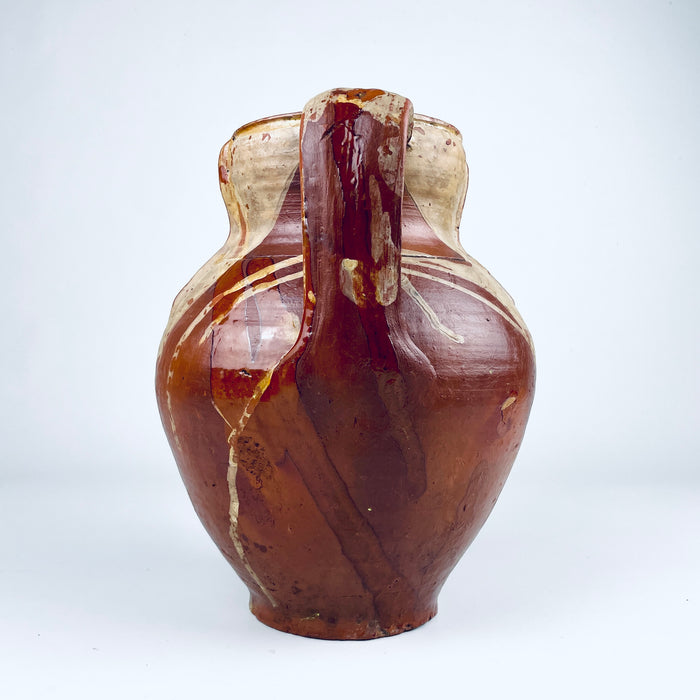 Nineteenth century Spanish terracotta vase measuring 24 cm tall, with a balanced two handled form, rounded shoulders and a flat base. The irregular amber and olive brown glaze flows across the upper red clay body while areas of exposed pottery create a graphic surface appropriate for Mediterranean decor, farmhouse decor and collected antique interiors.