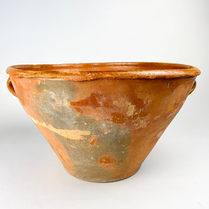 Large Spanish terracotta bowl with a deep conical profile, two opposing handles and a broad irregular lip, sourced in Cuenca and dated to the late 18th century. The exterior combines warm orange clay with grey-green patina, glaze traces and worn patches, creating a sculptural antique pottery vessel for farmhouse, rustic or Mediterranean decor.