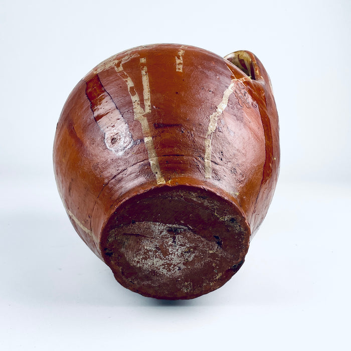 Base detail of an antique Spanish glazed terracotta orza jar, showing the flat circular foot, concentric wheel thrown lines and natural red clay surface. The utilitarian Castilian pottery construction supports its identity as a nineteenth century storage vessel, now suitable as a decorative vase for wabi sabi decor or rustic home decor.