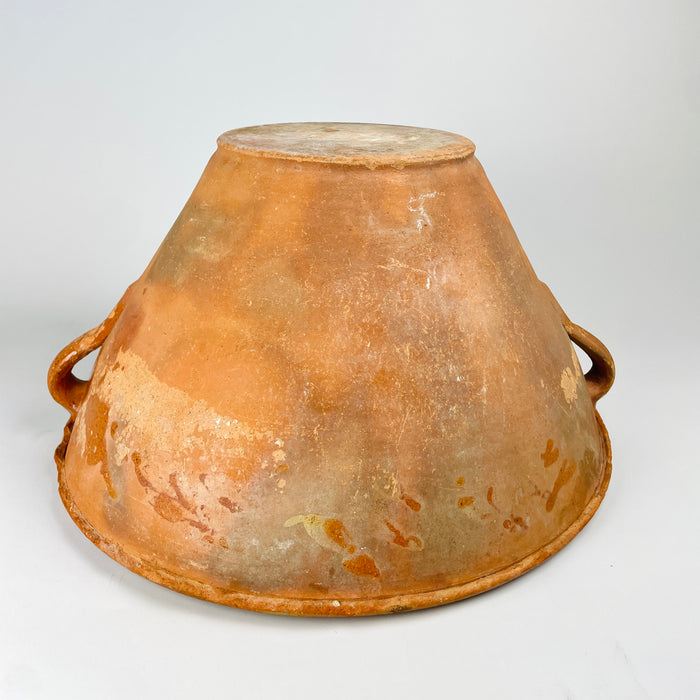 Late 18th century terracotta lebrillo showing the interior glaze as it follows the hand-thrown ridges from the broad rim toward the circular base. The amber surface varies from glossy to worn and matte, with small pits and age marks that contribute to the authentic patina of this Spanish folk pottery vessel for rustic and wabi sabi decor.