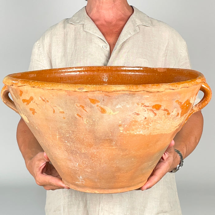 Large late 1700s Spanish terracotta lebrillo with a wide mouth, tapered lower body and balanced handles set beneath the rim. Generations of use have left layered ochre, grey and earthen tones across the exterior, while the interior retains a rich amber glaze and visible turning rings suited to wabi sabi decor and antique pottery collections.