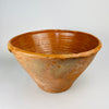 antique Spanish lebrillo bowl, formed from thick terracotta and joined beneath the broad rolled rim. The handle retains amber glaze, kiln speckling and wear from prolonged use, while the surrounding exterior shows layered patina, glaze drips and surface abrasion characteristic of an old working pottery vessel.