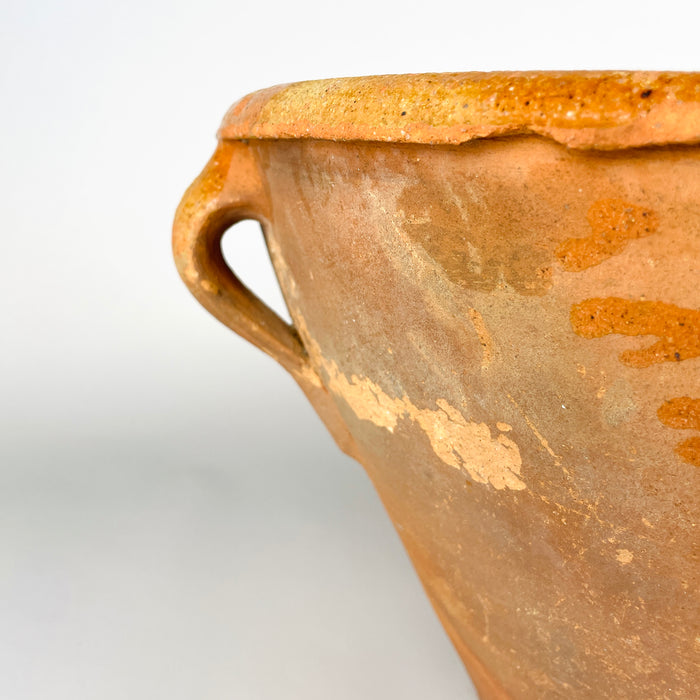 Late 18th century Spanish terracotta bowl, with an irregular hand-shaped profile and glazed surface worn back to the clay along raised areas. The adjoining rim carries chips, glaze losses and warm ochre variation, documenting the handmade construction and generations of use that distinguish this antique lebrillo.