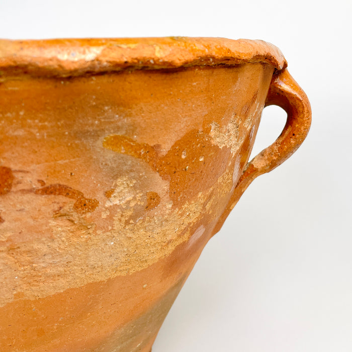 Antique XL lebrillo bowl in Spanish terracotta, covered with a warm honey-brown glaze over clearly visible concentric wheel marks. Areas of rubbing, mineral residue and glaze thinning reveal the vessel’s long domestic history, while the deep rounded form offers strong decorative potential as a large centerpiece or sculptural pottery vase.