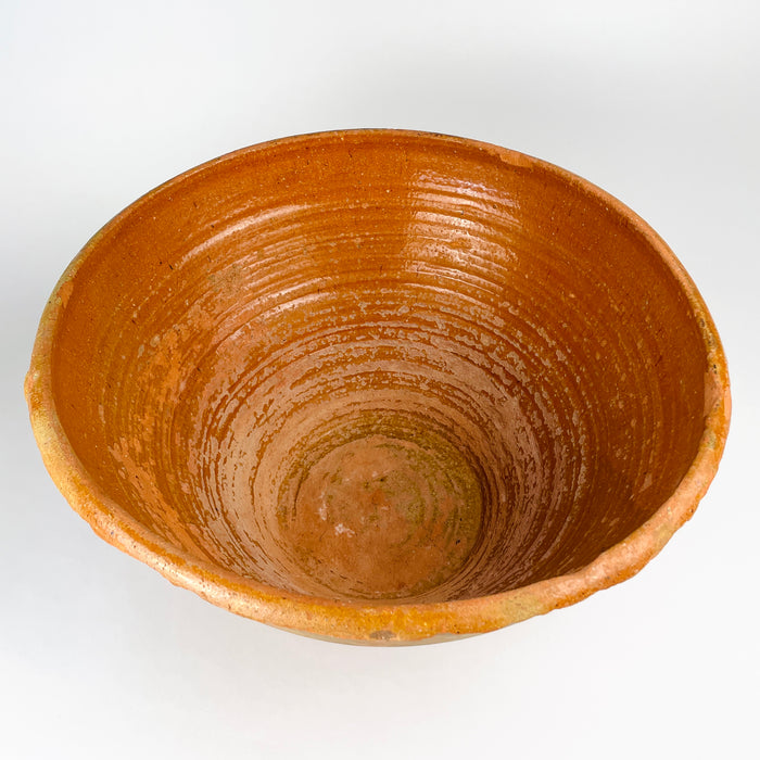 Late 18th century Spanish lebrillo bowl, showing hand-shaped clay, amber glaze, kiln speckling and age-related wear. The thick handle is integral to the vessel’s extremely uncommon two-handled form, a defining feature that separates this substantial antique from more typical shallow, handleless lebrillos.