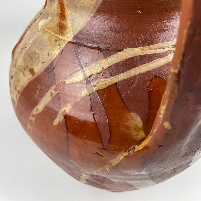 Antique Spanish pottery vase with a bulbous body tapering to a flat circular base, a short open neck and two high loop handles. The partially glazed terracotta surface combines amber, olive brown and warm red clay, creating a distinctive Castilian orza jar for a console, shelf or dining room centerpiece in Mediterranean decor.