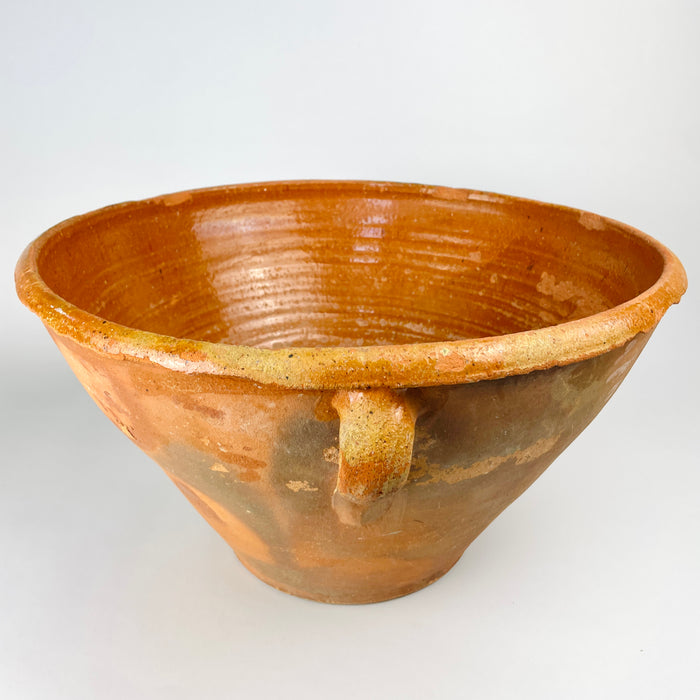Large Spanish terracotta bowl with a deep conical profile, two opposing handles and a broad irregular lip, sourced in Cuenca and dated to the late 18th century. The exterior combines warm orange clay with grey-green patina, glaze traces and worn patches, creating a sculptural antique pottery vessel for farmhouse, rustic or Mediterranean decor.