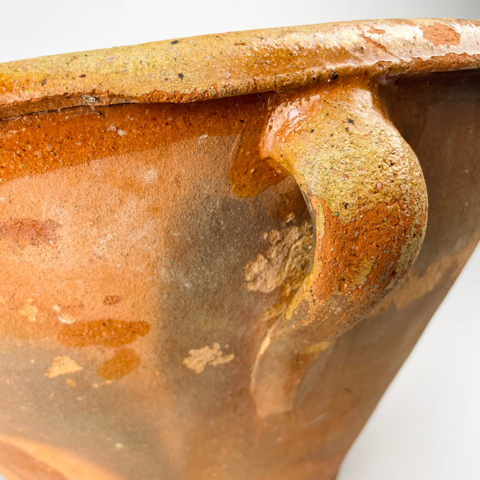 Late 18th century terracotta lebrillo showing the interior glaze as it follows the hand-thrown ridges from the broad rim toward the circular base. The amber surface varies from glossy to worn and matte, with small pits and age marks that contribute to the authentic patina of this Spanish folk pottery vessel for rustic and wabi sabi decor.