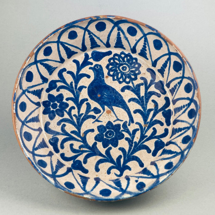 Antique Spanish Fajalauza lebrillo bowl from the late 19th century, hand-painted with a cobalt bird surrounded by Moorish floral scrolls and borders, showcasing Andalusian ceramic artistry in blue over white tin-glaze on terracotta.