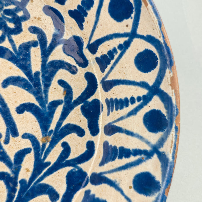 Close-up of the geometric border pattern running around the bowl's edge, featuring repeating cobalt blue leaf-like swirls influenced by Islamic decorative arts, typical of Moorish ceramic traditions in southern Spain.