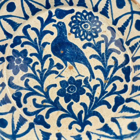 Close-up of the hand-painted central bird in the antique lebrillo, showing expressive brushstrokes and glaze pooling in cobalt blue, with visible patina and irregularities that reflect its 19th-century origin and handcrafted nature.