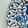 Glaze pooling and softened brushwork near the bowl's inner rim, showing the hallmarks of antique Andalusian pottery including age-worn edges, cobalt bleed, and freehand symmetry in floral scrolls.